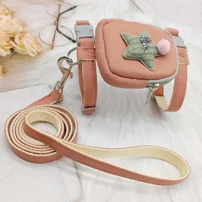 A chic Dog Traction Rope Adjustable Pet Knapsack in pink, featuring a small pouch adorned with a star and the word "Love." The harness is equipped with metal buckles and includes a matching leash. Nearby, there are glasses, a white notebook, and light-colored flowers on a soft surface.